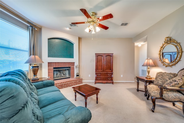 living room featuring ceiling fan, a brick fireplace, and light carpet