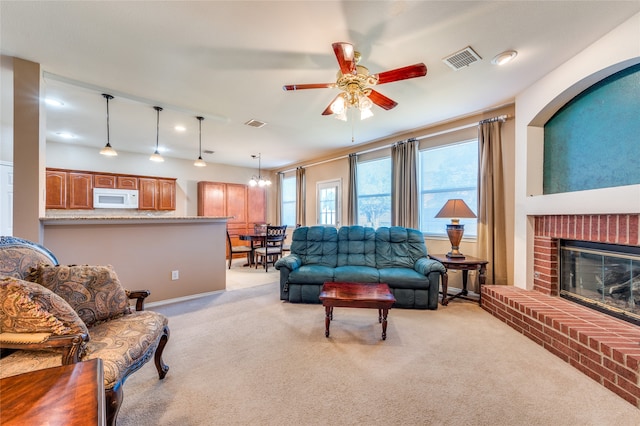 living room with light carpet, a fireplace, and ceiling fan