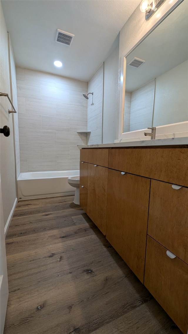 full bathroom with wood-type flooring, vanity, toilet, and tiled shower / bath