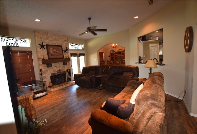 living room with ceiling fan, a fireplace, and dark wood-type flooring