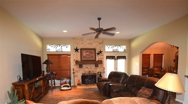 living room with a stone fireplace, ceiling fan, and hardwood / wood-style flooring