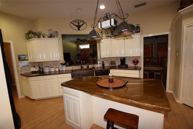 kitchen featuring ceiling fan, light hardwood / wood-style floors, a center island, and tasteful backsplash