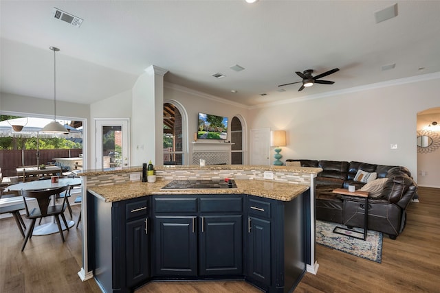 kitchen with ceiling fan, a center island with sink, hanging light fixtures, and light stone counters