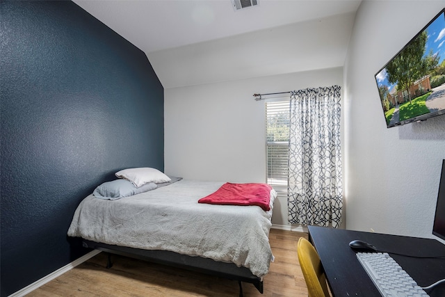 bedroom with hardwood / wood-style flooring and lofted ceiling