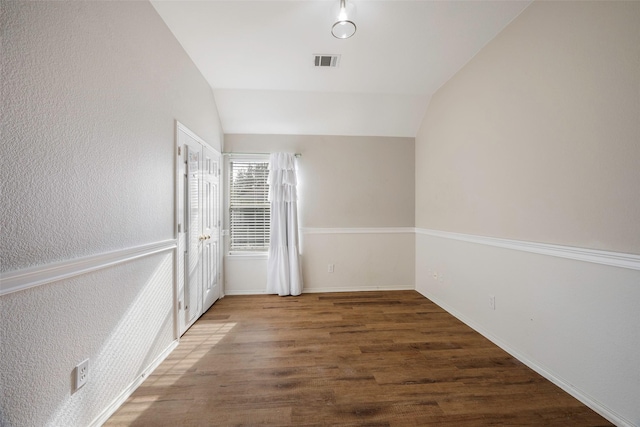 spare room featuring dark hardwood / wood-style flooring and lofted ceiling