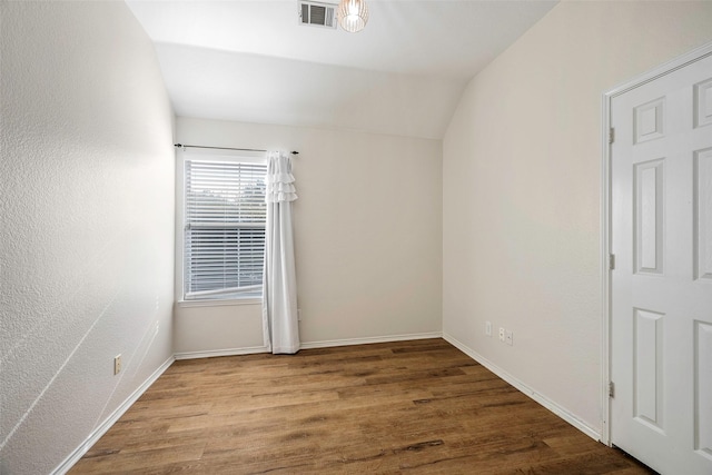 empty room with hardwood / wood-style floors and vaulted ceiling