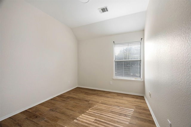 empty room with light wood-type flooring and vaulted ceiling