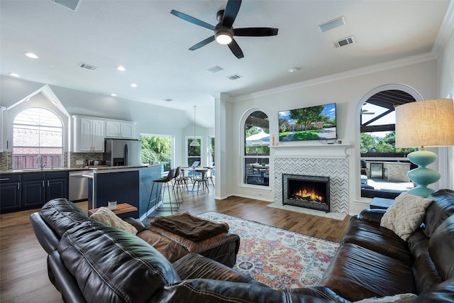 living room featuring ceiling fan, sink, a wealth of natural light, and a tiled fireplace