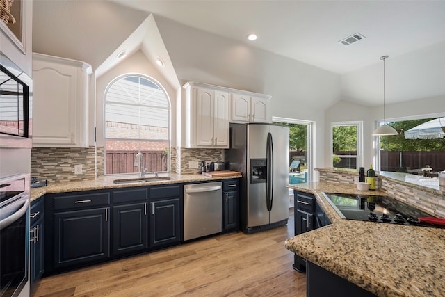 kitchen with sink, stainless steel appliances, tasteful backsplash, lofted ceiling, and white cabinets