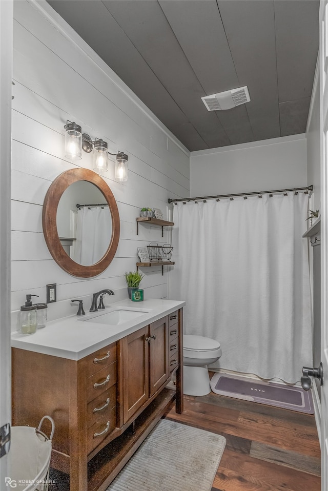 full bathroom with wood-type flooring, wooden walls, shower / tub combo, vanity, and toilet