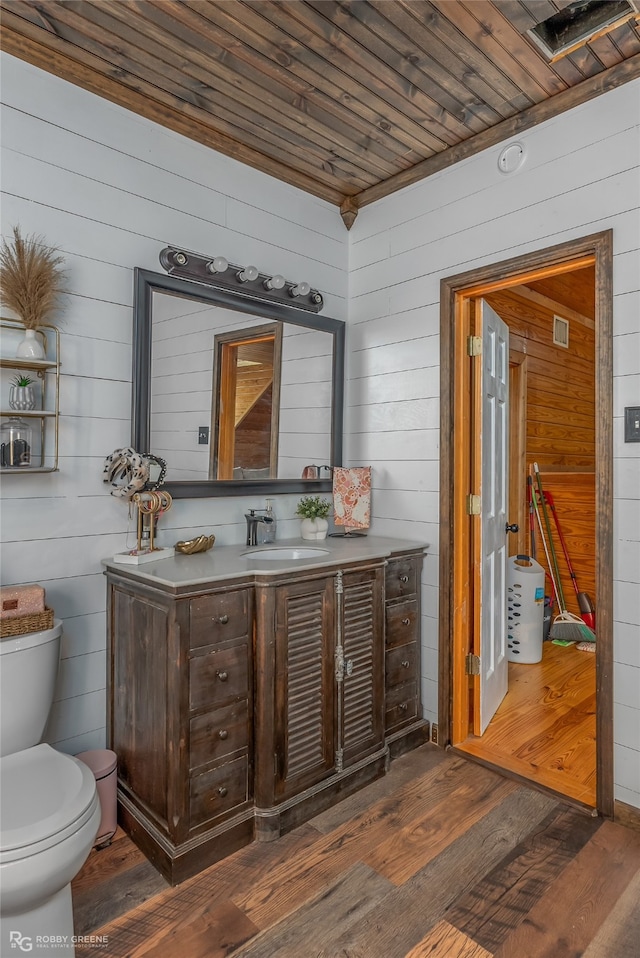 bathroom featuring wood walls, vanity, toilet, and hardwood / wood-style flooring