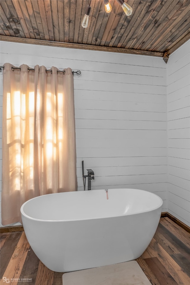 bathroom with hardwood / wood-style floors, wood walls, and a washtub