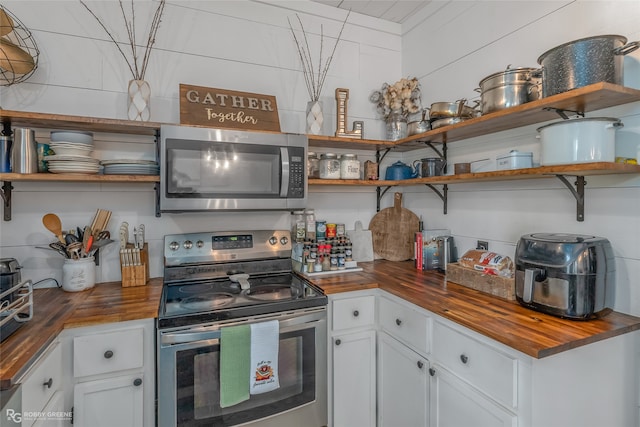 kitchen with stainless steel appliances, white cabinetry, and wood counters