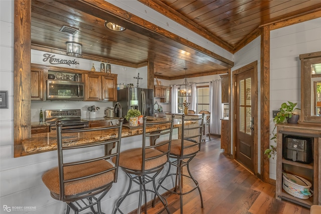 kitchen featuring wood ceiling, pendant lighting, a kitchen breakfast bar, stainless steel appliances, and dark hardwood / wood-style flooring