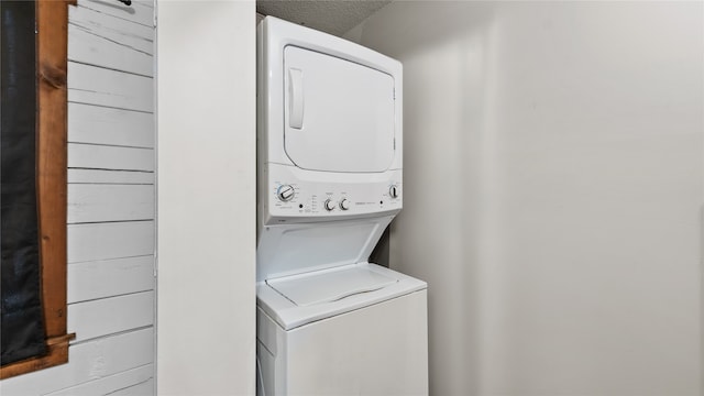 laundry area featuring stacked washer and clothes dryer and a textured ceiling