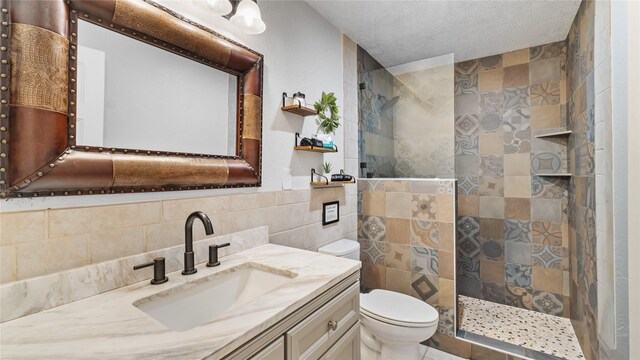 bathroom featuring tile walls, a textured ceiling, tiled shower, vanity, and toilet