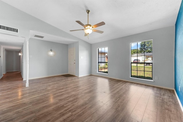 empty room with ornate columns, lofted ceiling, hardwood / wood-style floors, and ceiling fan