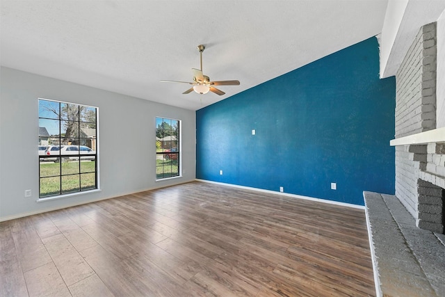 unfurnished living room with ceiling fan, hardwood / wood-style floors, a textured ceiling, and a fireplace