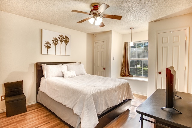 bedroom with a textured ceiling, light hardwood / wood-style floors, and ceiling fan