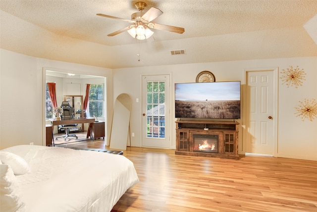 bedroom featuring ceiling fan, a textured ceiling, light hardwood / wood-style flooring, and access to outside