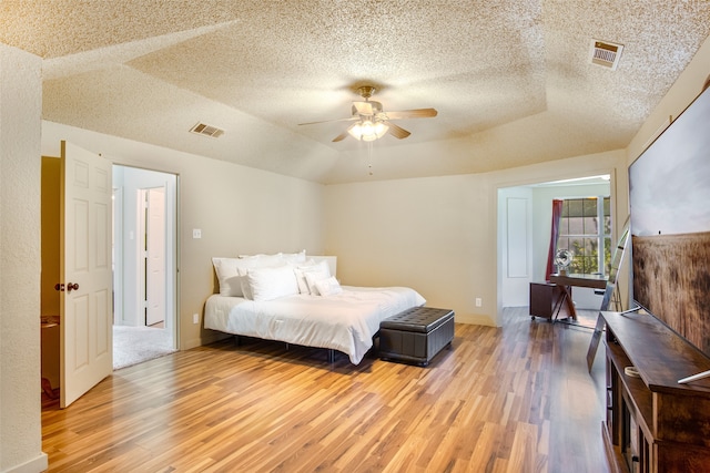 bedroom with ceiling fan, a textured ceiling, and light hardwood / wood-style flooring