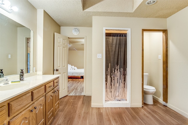 bathroom with a textured ceiling, vanity, toilet, and hardwood / wood-style flooring