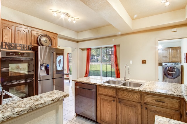 kitchen featuring appliances with stainless steel finishes, light tile patterned floors, a textured ceiling, washer / dryer, and sink