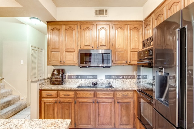 kitchen with light stone countertops, black appliances, and light tile patterned flooring