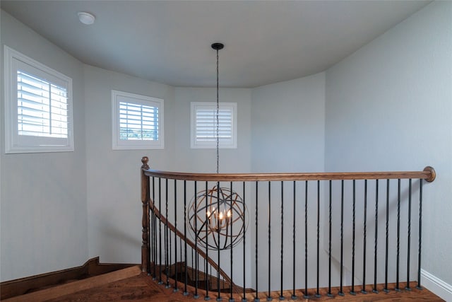 stairs with wood-type flooring and a notable chandelier