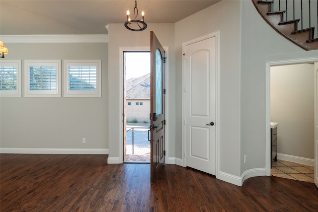 foyer entrance featuring a notable chandelier, dark hardwood / wood-style floors, and crown molding