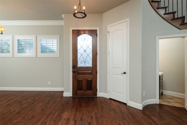 entrance foyer with ornamental molding, a notable chandelier, and dark hardwood / wood-style flooring