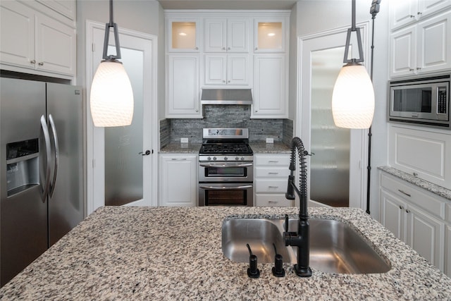 kitchen with pendant lighting, white cabinets, exhaust hood, and appliances with stainless steel finishes