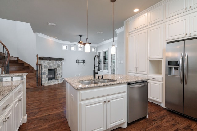 kitchen with sink, stainless steel appliances, decorative light fixtures, a stone fireplace, and ceiling fan