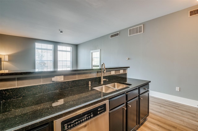 kitchen featuring sink, stainless steel dishwasher, dark stone counters, and light hardwood / wood-style flooring