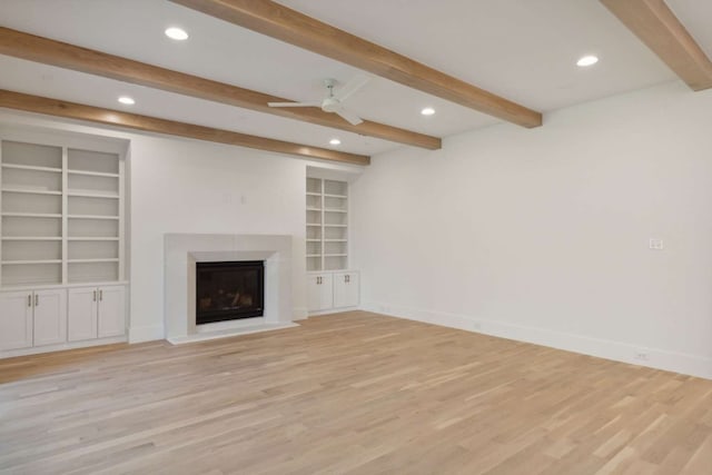 unfurnished living room with beamed ceiling, ceiling fan, built in shelves, and light hardwood / wood-style flooring