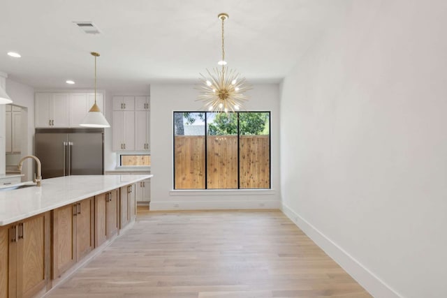 kitchen featuring a chandelier, white cabinets, hanging light fixtures, light hardwood / wood-style flooring, and built in fridge