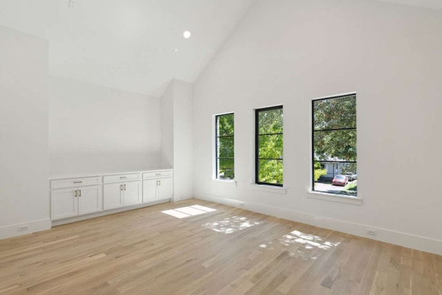 spare room with high vaulted ceiling and light hardwood / wood-style floors