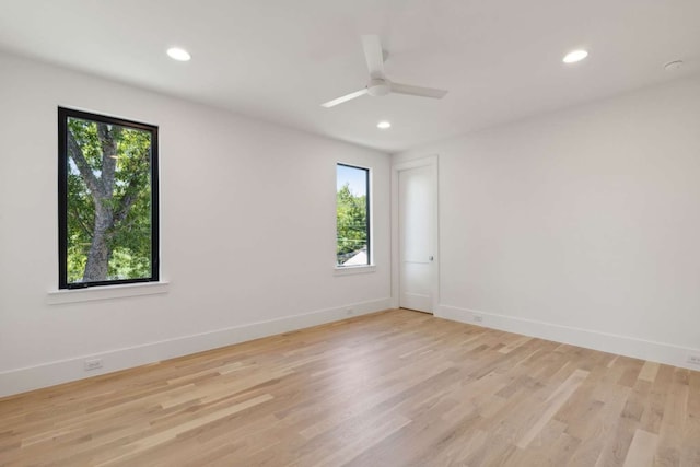 spare room with light wood-type flooring, a healthy amount of sunlight, and ceiling fan