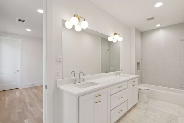 full bathroom with vanity, tiled shower / bath combo, toilet, and hardwood / wood-style flooring