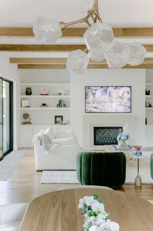 living room featuring beam ceiling, hardwood / wood-style floors, and built in features