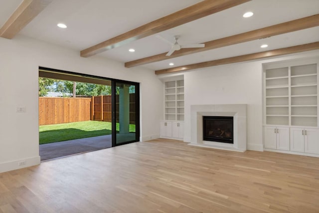 unfurnished living room featuring beamed ceiling, ceiling fan, built in features, and light hardwood / wood-style flooring