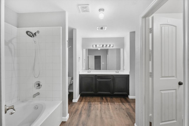 full bathroom featuring toilet, tiled shower / bath combo, vanity, and hardwood / wood-style floors