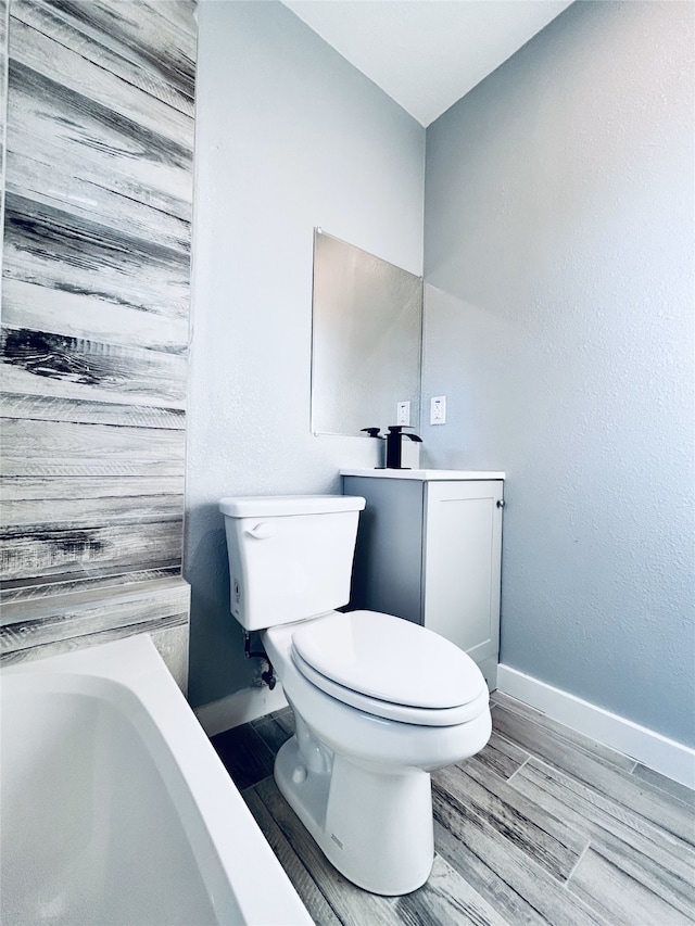 bathroom with vanity, toilet, a tub, and hardwood / wood-style flooring