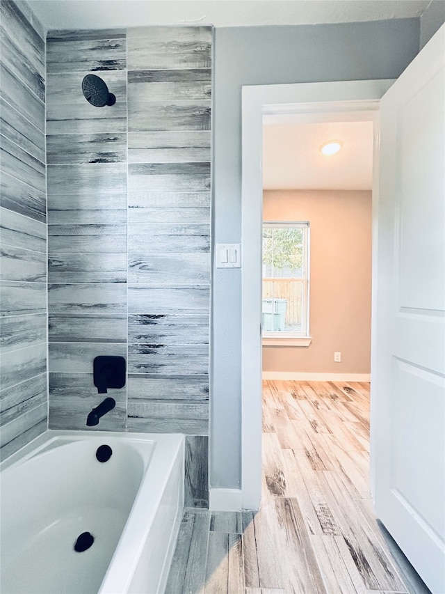 bathroom with hardwood / wood-style flooring and tiled shower / bath