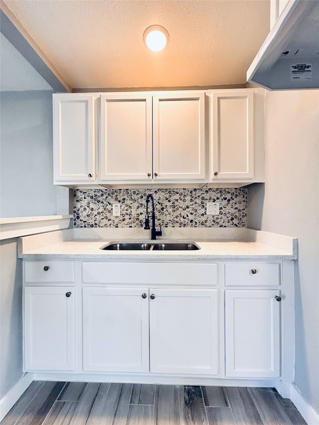 kitchen featuring range hood, white cabinetry, tasteful backsplash, and sink