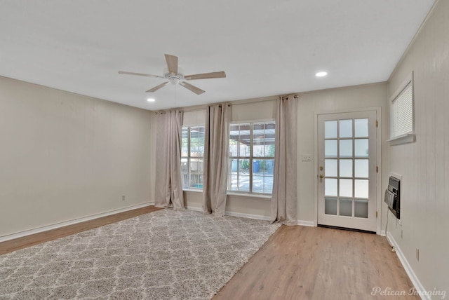 doorway to outside with ceiling fan, heating unit, plenty of natural light, and light hardwood / wood-style floors