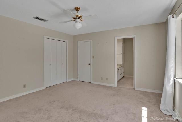 unfurnished bedroom with light carpet, connected bathroom, and ceiling fan