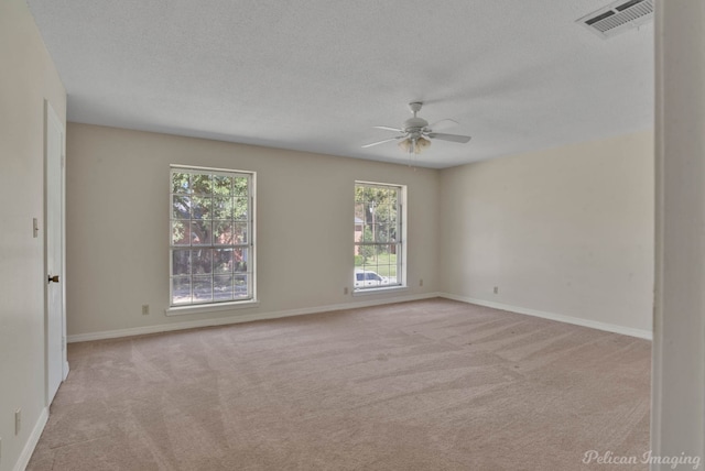 unfurnished room featuring ceiling fan, light colored carpet, and a textured ceiling