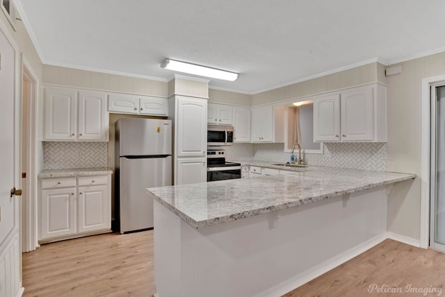 kitchen with stainless steel appliances, kitchen peninsula, tasteful backsplash, and white cabinetry