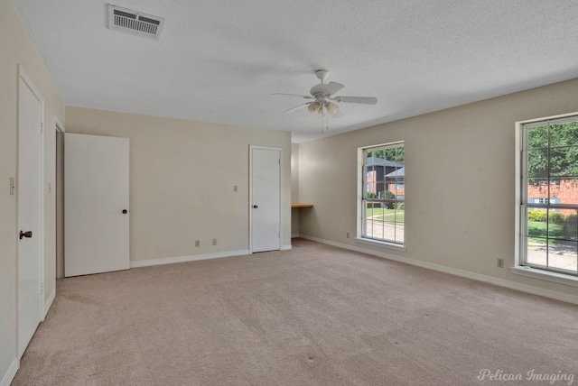 spare room featuring a textured ceiling, light carpet, and ceiling fan